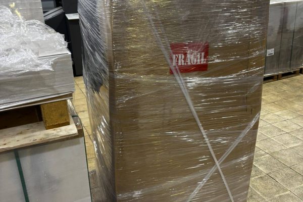 Groupage import pallet wrapped in plastic with fragile label inside UK warehouse