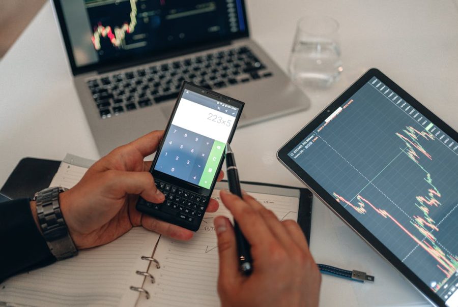 Man using a calculator to calculate landed cost and import charges at a desk