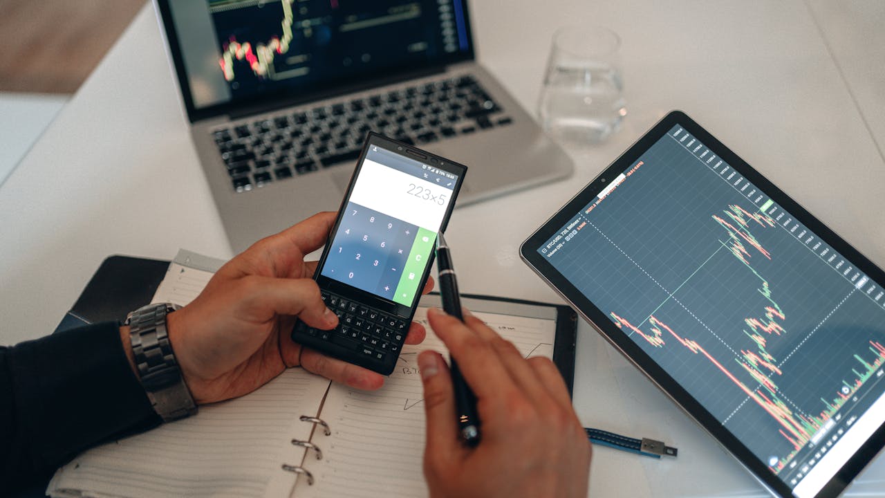 Man using a calculator to calculate landed cost and import charges at a desk