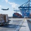Cargo pallets at a port with a freight aircraft and container ship