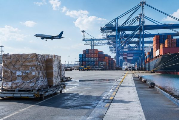 Cargo pallets at a port with a freight aircraft and container ship
